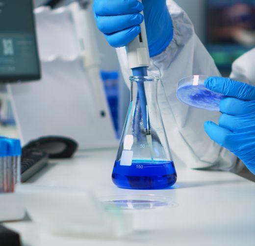 Close up of science technician in ppe suit using a pipette with a microtiter plate and a petri dish working in laboratory. Team examining virus evolution for vaccine development against covid19